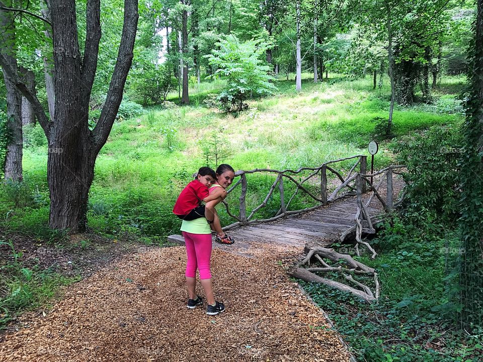 After a long hike, big sister carried baby brother over the bridge.