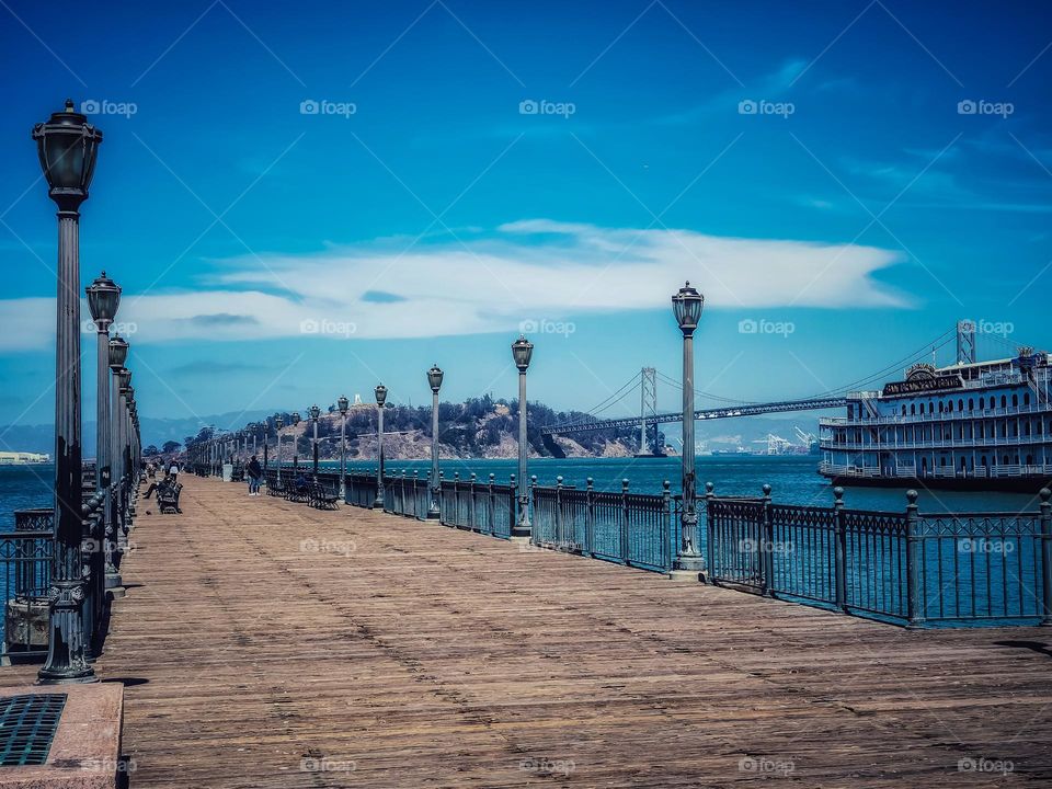 View down pier 7 in San Francisco California, with the San Francisco Bay, treasure island, and the Bay Bridge. 