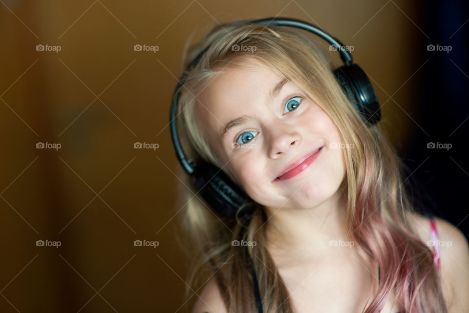 Cute kid girl listening music in stereo headset