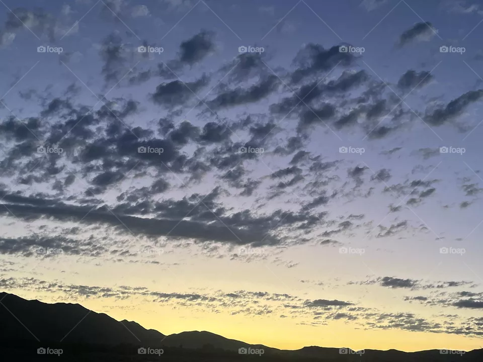 A yellow sunset with clouds and mountains.