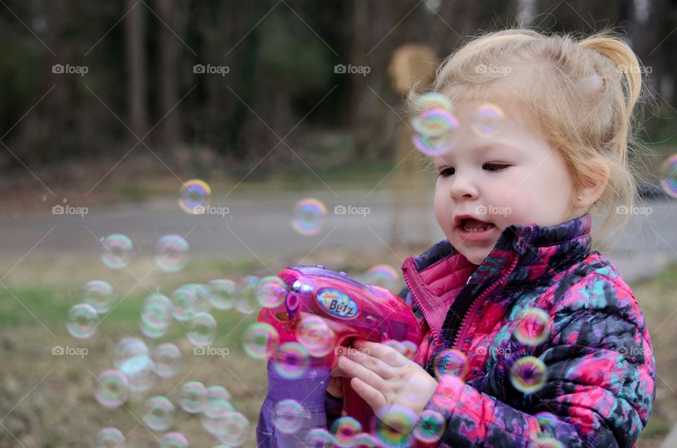 Blonde girl shooting bubble from bubble gun