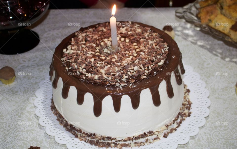 Feliz aniversário! Bolo branco com chocolate derretido e vela acesa para comemorar aniversário! 