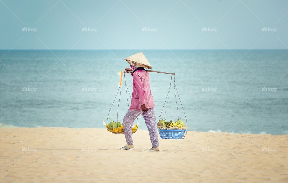 Vietnamese woman with fruits on the beach 