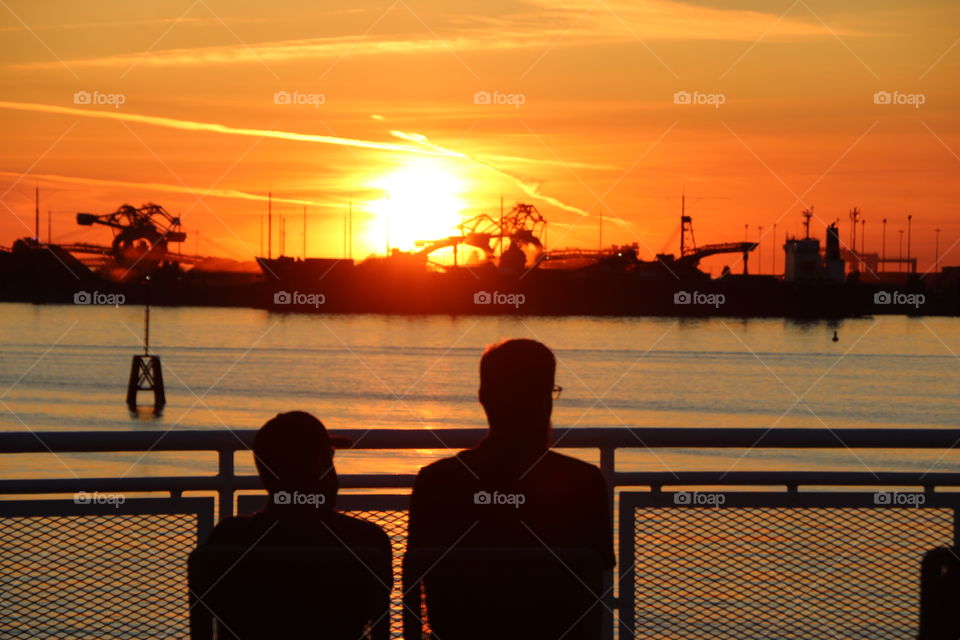 Silhouettes of people on a ferry docking during sunset 