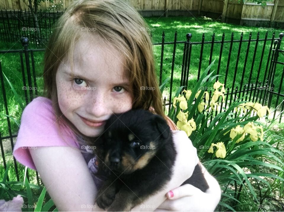 Young Girl Holding Puppy In Courtyard 