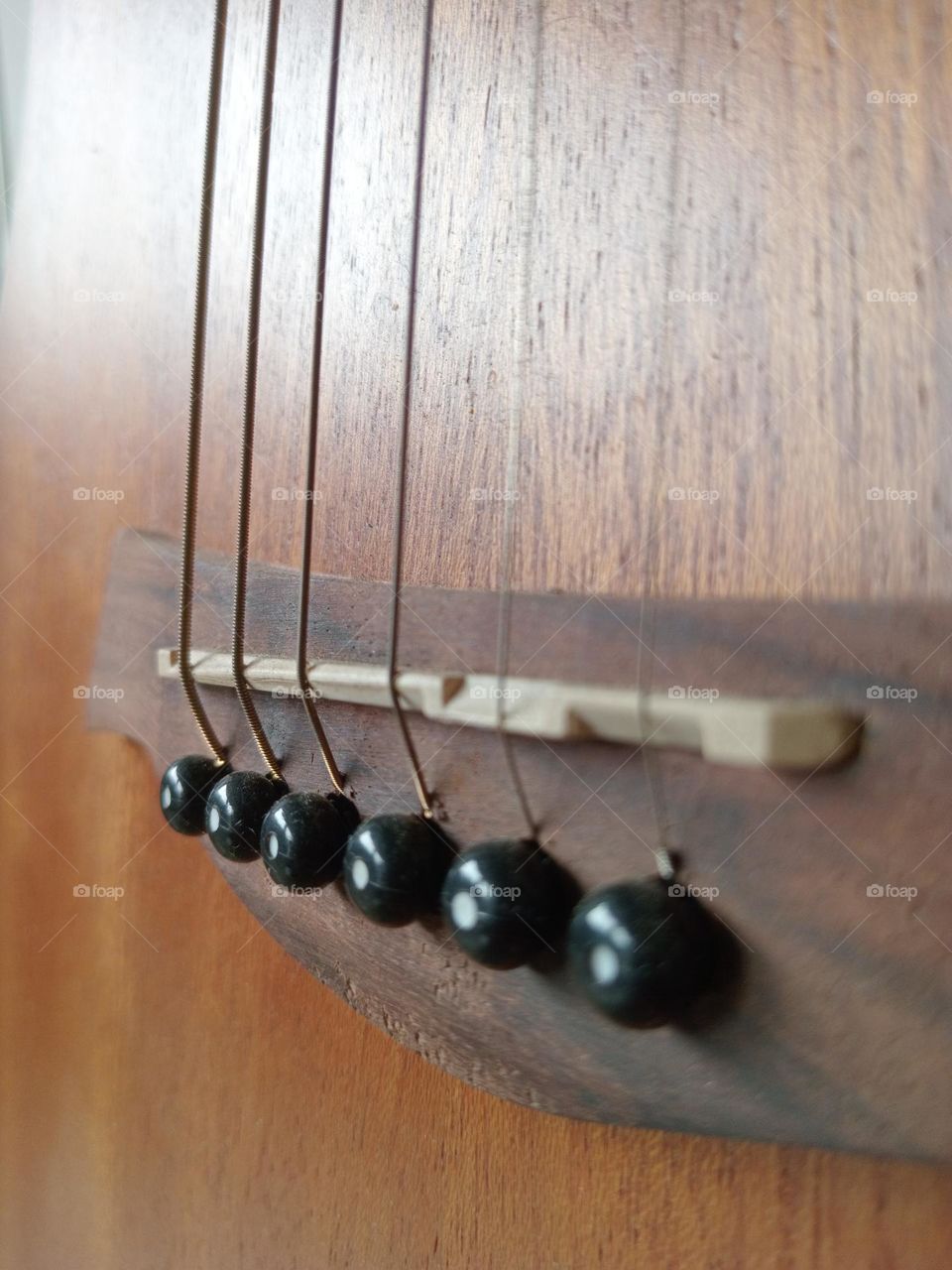 An acoustic guitar is a type of guitar where the sound produced comes from the vibration of the guitar strings that are channeled through the saddle and bridge where the strings are attached into the sound chamber