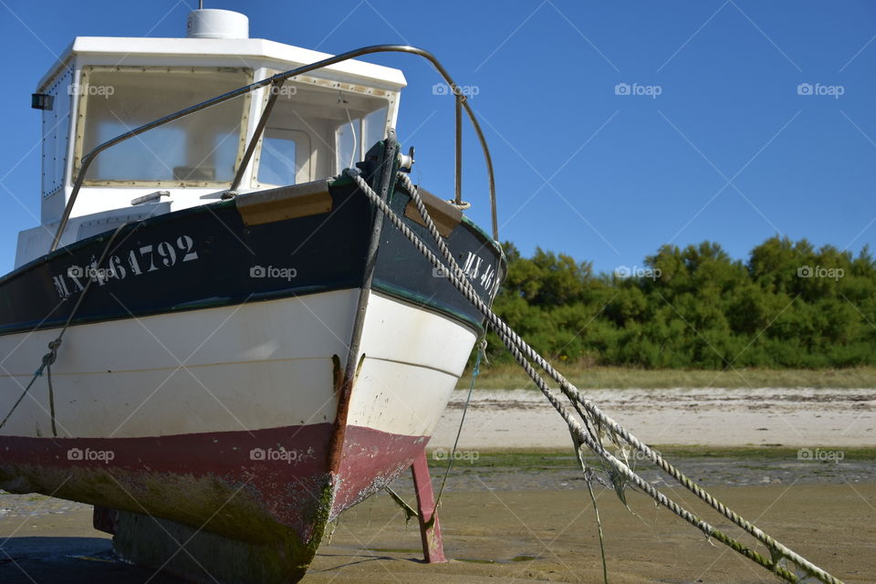 Ship lying on sand during low tide as symbol for not traveling 