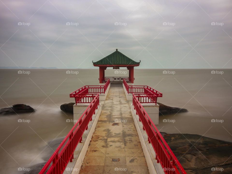 Scenic scene of a beach gazebo in a cloudy sunrise.