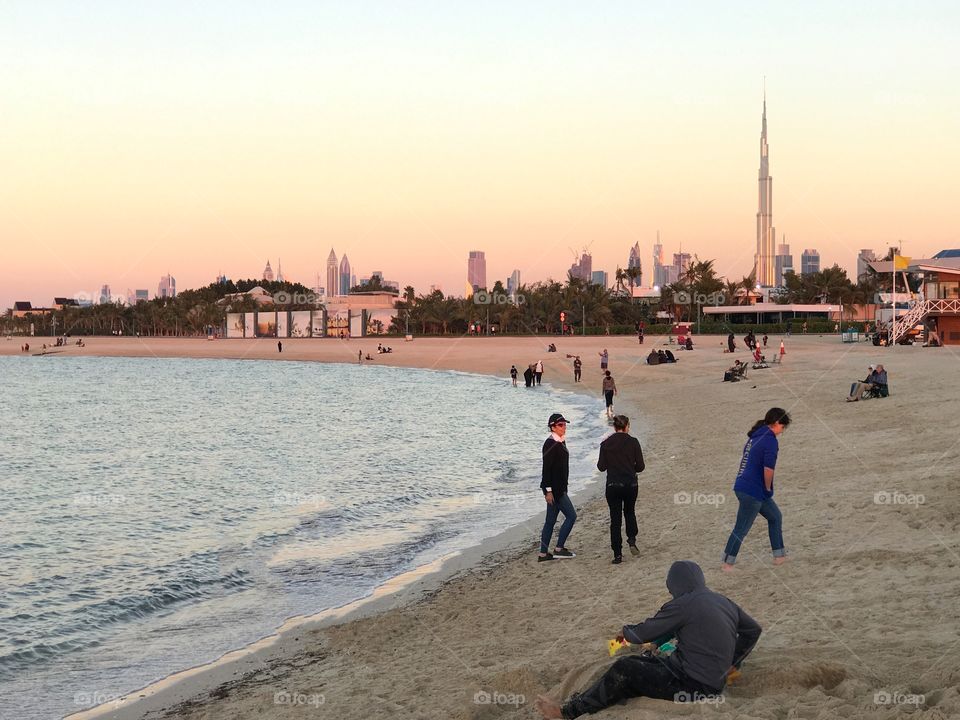 People enjoying at the beach during the golden hour in Dubai with Burj Khalifa seen in the background 
