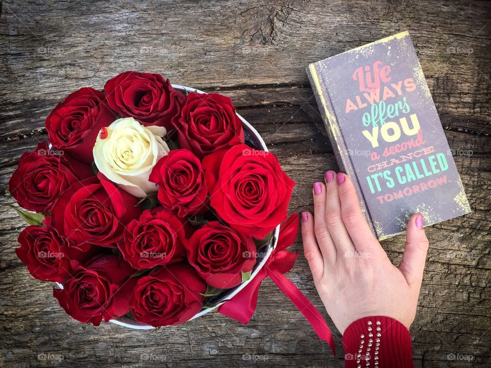 Woman hand with pink nails near a book with a motivational qoute:Life always offers you a second chance it s called tomorrow