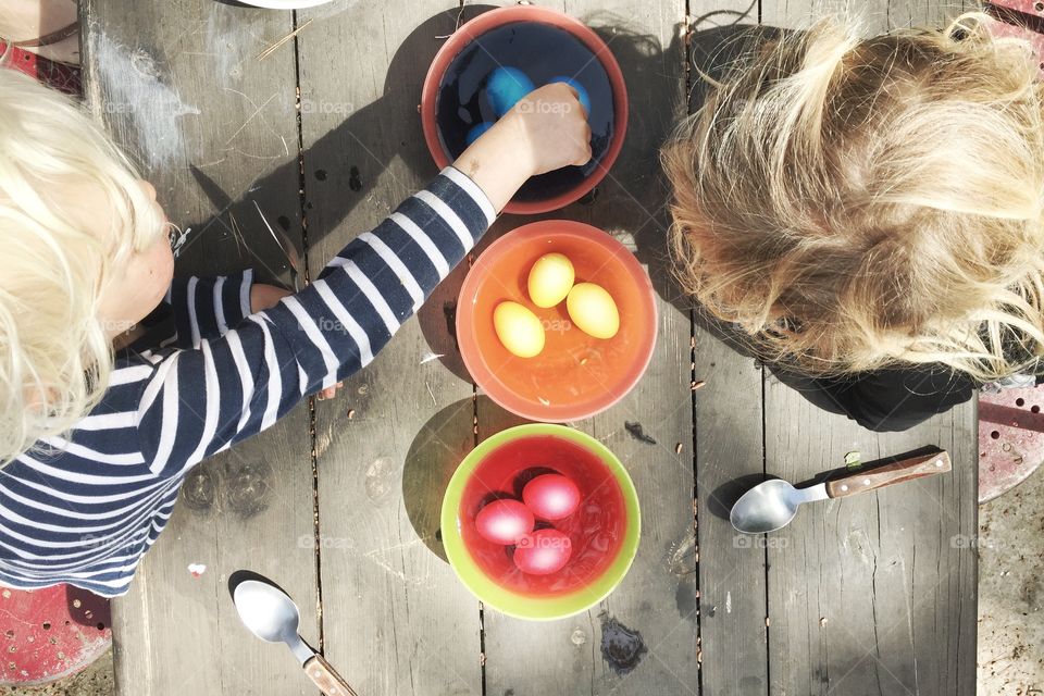 Girls playing with colorful Easter eggs in bowl of water