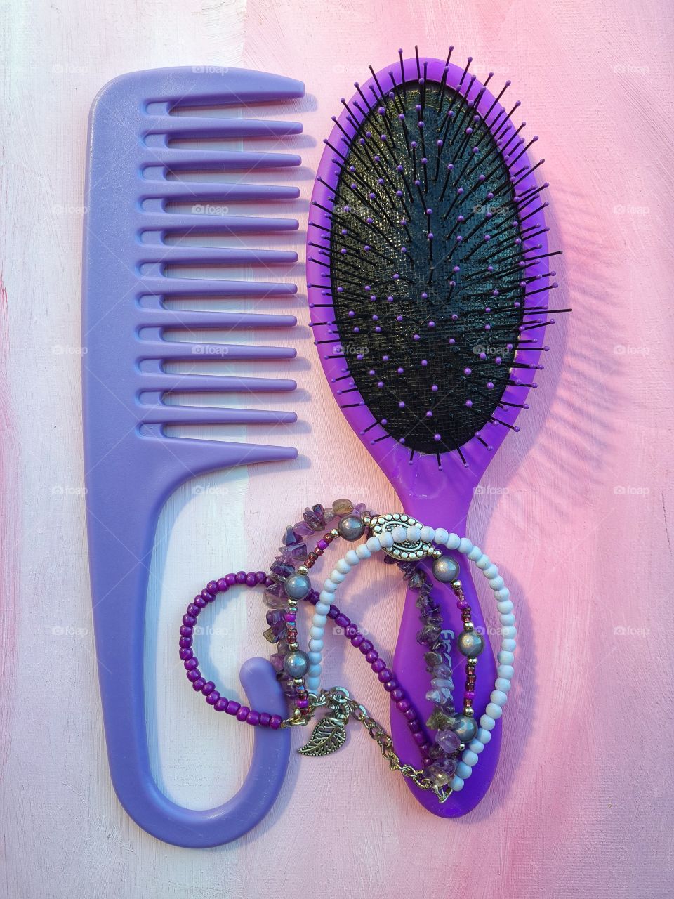 wide tooth purple hair comb and a purple hair brush with a beautiful bracelet made out of different shades and shapes of beads