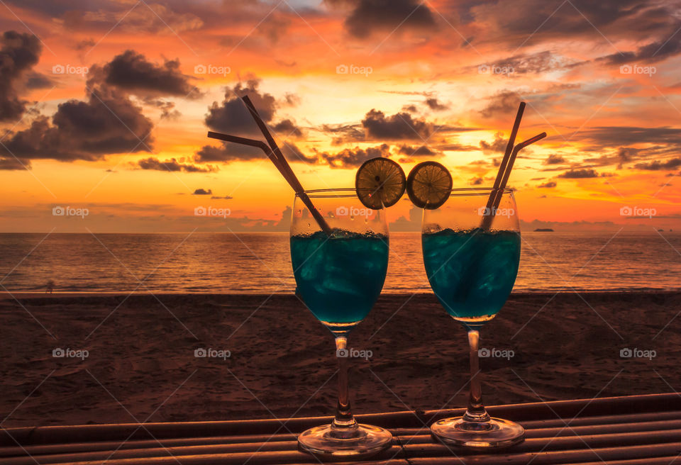 Drink together at golden hour. Cocktails with friend on tropical beach in Thailand at sunset golden hour