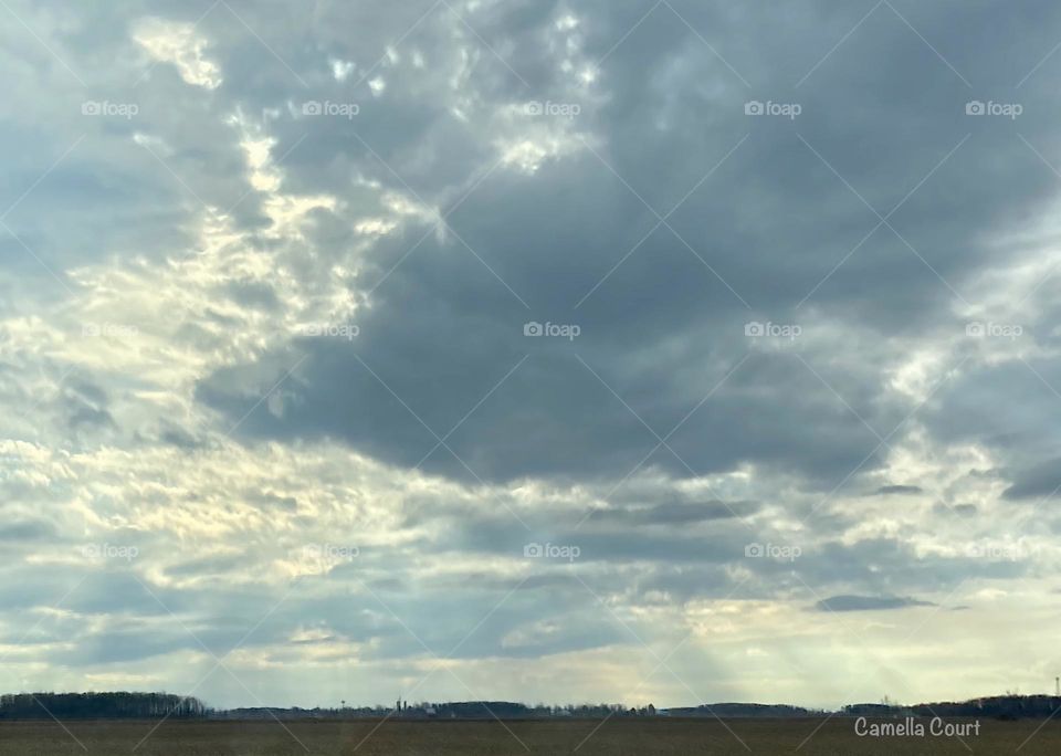 Sunrise breaking through the clouds after a storm over farm land