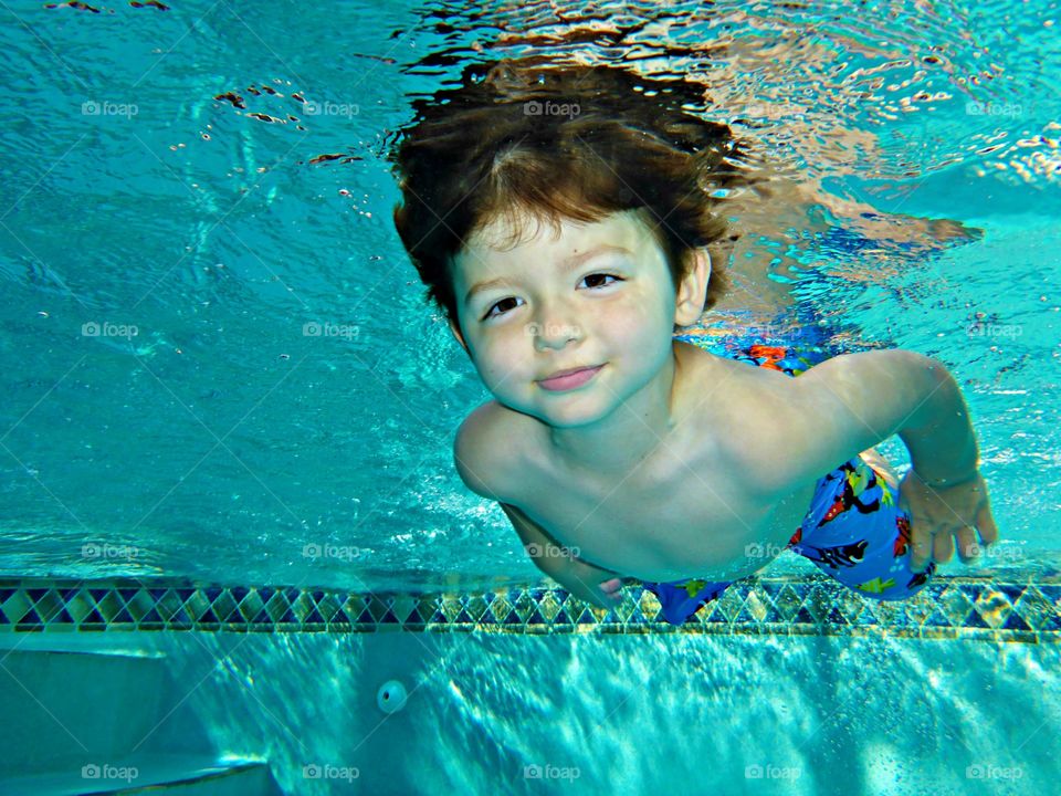 Cute boy swimming underwater in pool