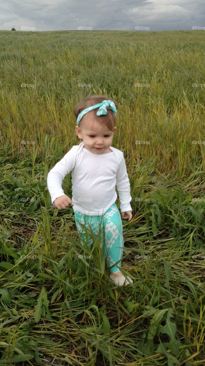 Little girl walking in grassy field