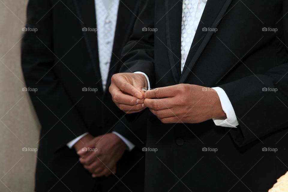 A groom holds his soon to be wife wedding ring in his hand.