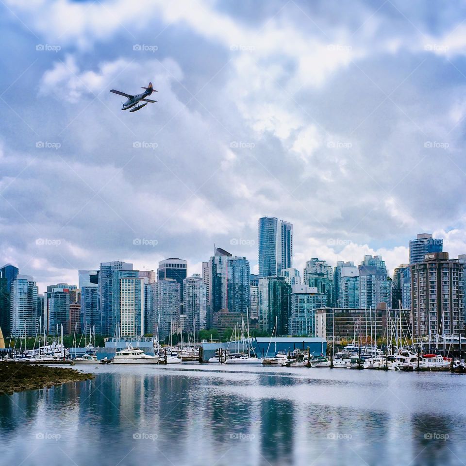 A plane flies over Victoria, British Columbia on a beautiful day, the city illuminated by the blue sky