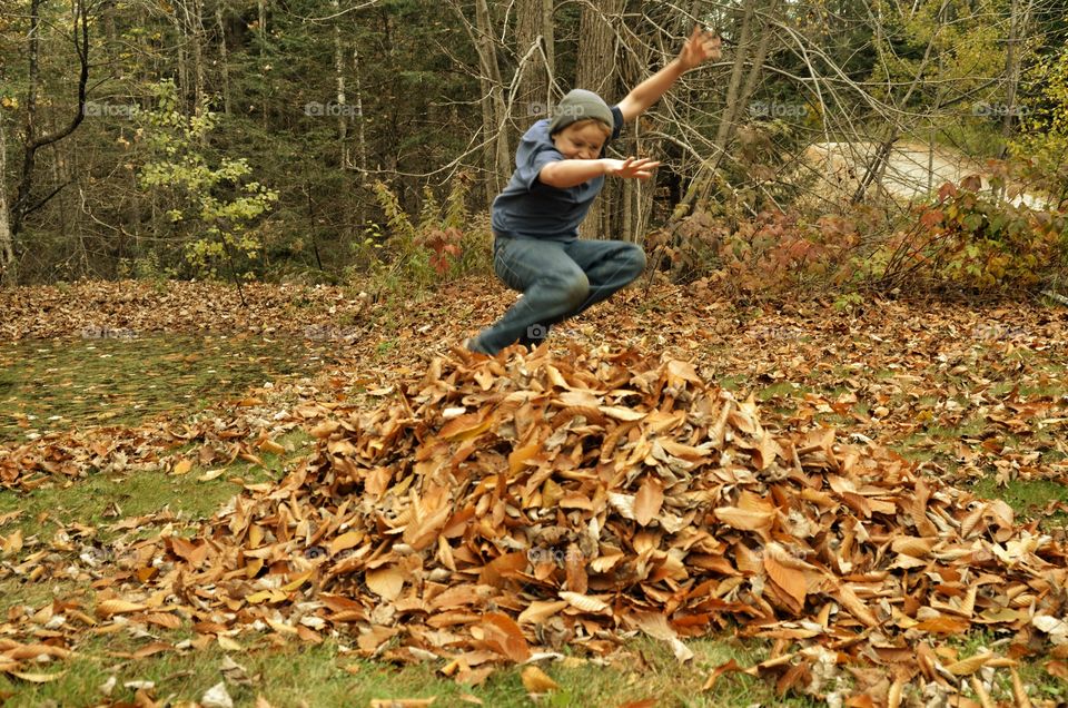 Boy playing over the heap of autumn leaves