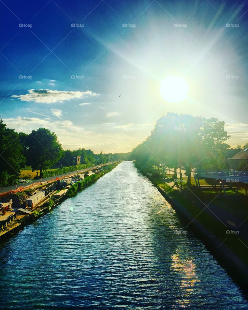 Brightly shining sun in a blue sky above a Countryside river landscape 