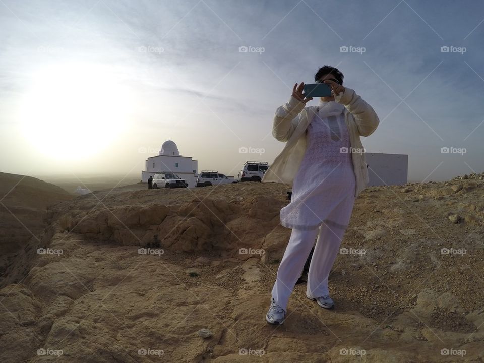 Lady / woman taking pictures with her iPhone in the Sahara desert in Tunisia