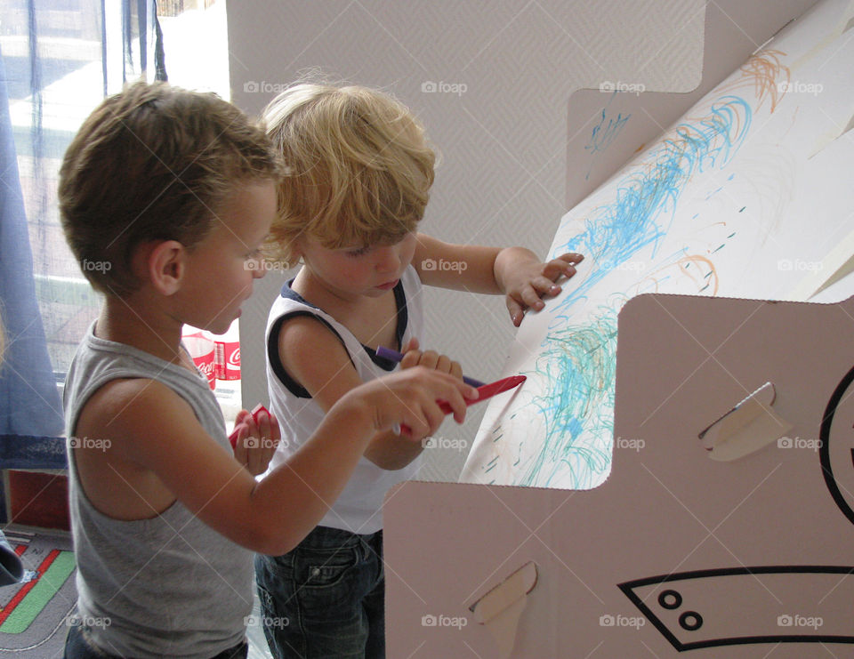 2 friends drawing on the big cardbox-house. Children playing together 