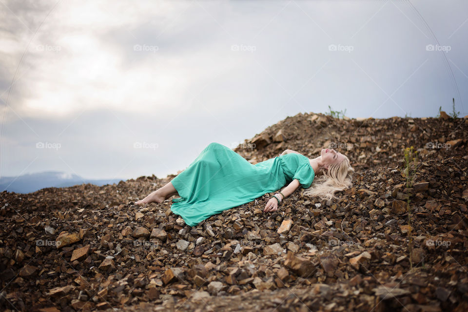 Blonde woman lying on rock stones