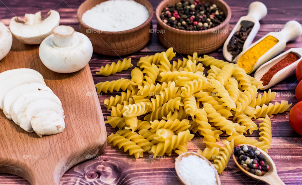 Raw pasta with ingredients and wooden accessories