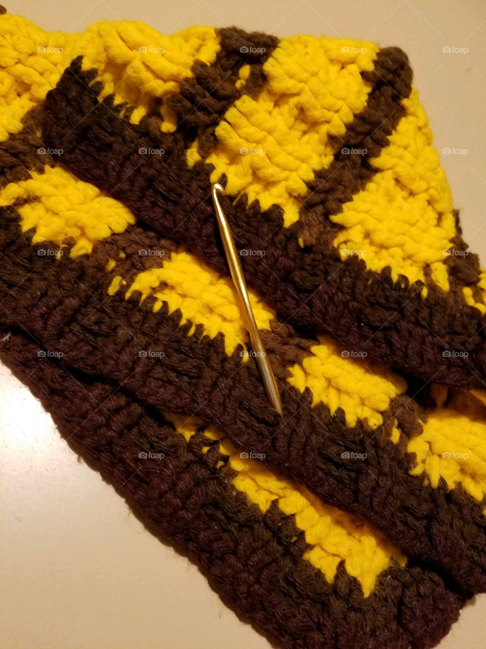 Crocheted Afghan blanket from leftover yarns. Gold colored crochet hook used to make this.