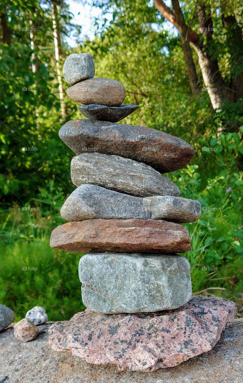 The strength and balance of 9 stones! Pyramid of stones on the coast of the Gulf of Finland (Baltic sea) against the background of forest