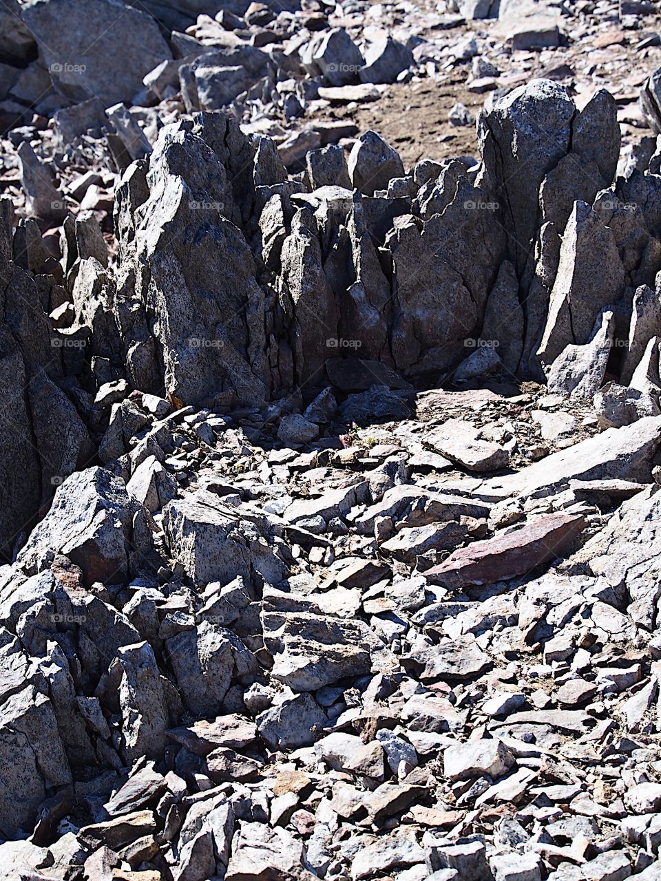 Jagged rocks and boulders along the shoreline of Ochoco Lake in Central Oregon on a sunny spring day.