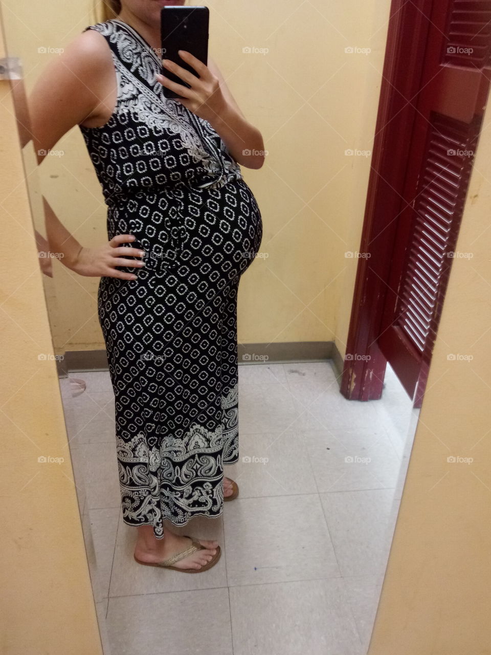 a young pregnant mom trying on stylish clothes in a fitting room.