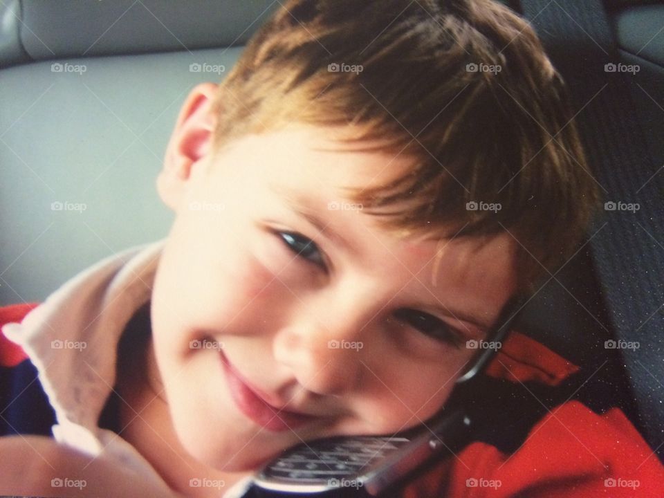 A little boy talking with mobile phone in car