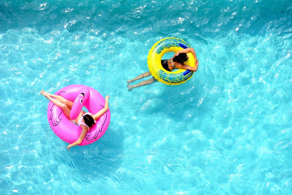 View looking down on two girls floating in a swimming pool.