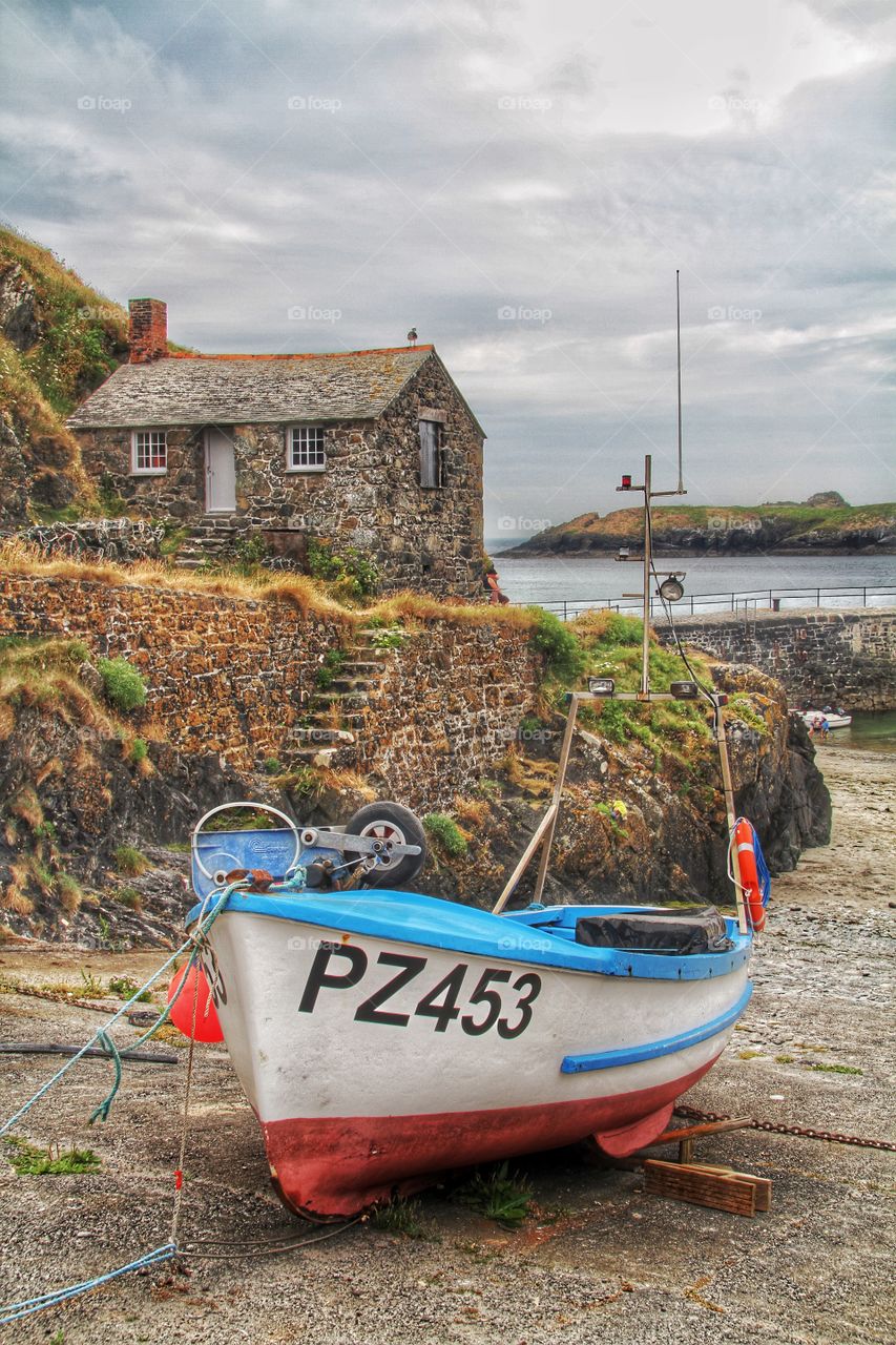 Fishing Boat and harbourmaster. A colourful fishing boat beached in the harbour with a netloft behind.