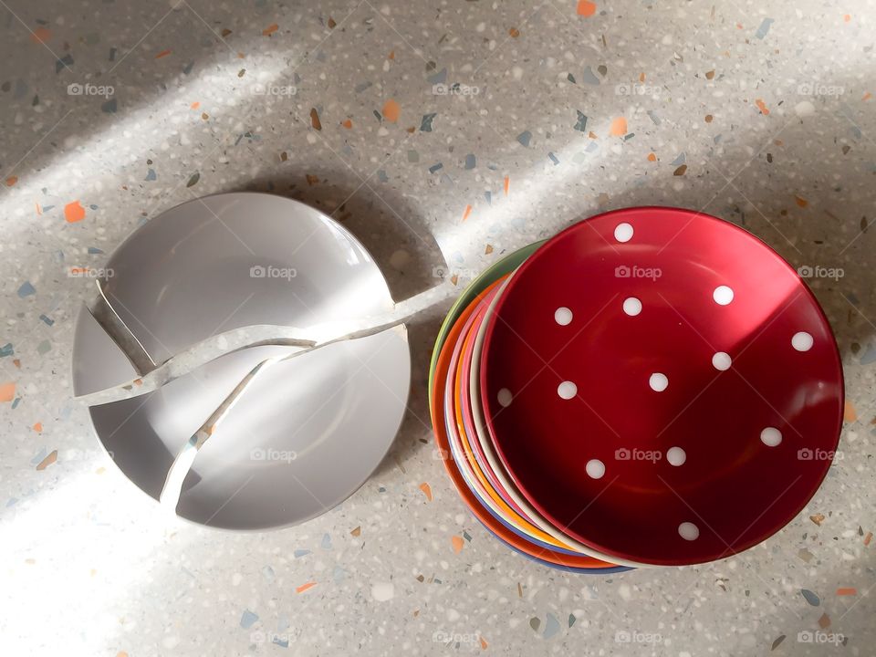 Broken dish and a stack of plates on the table