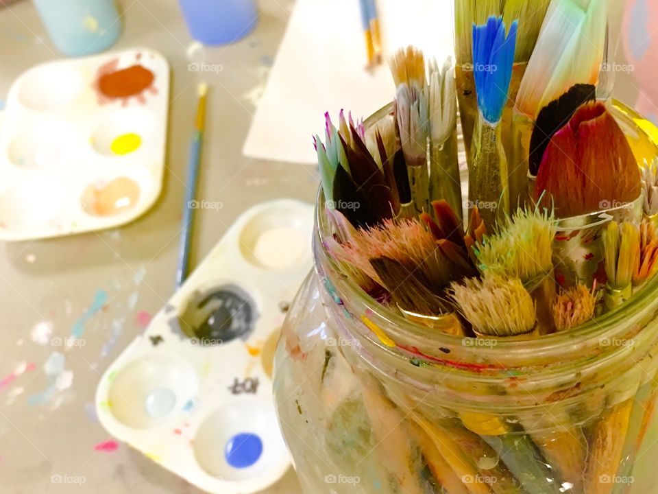 Set of used paint brushes in glass jar