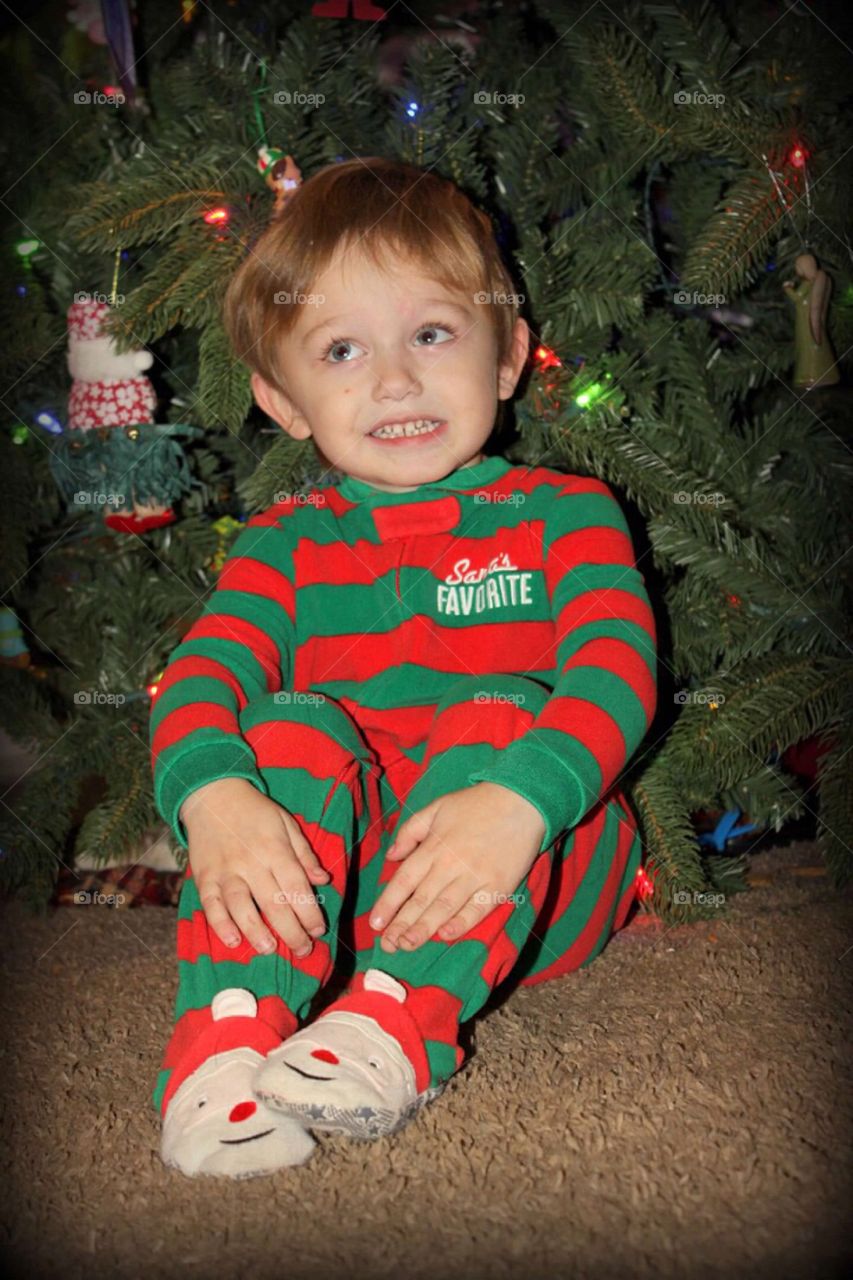 Boy sitting in front of Christmas tree