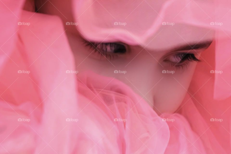 the girl is covered with a pink cloth, only her eyes are visible