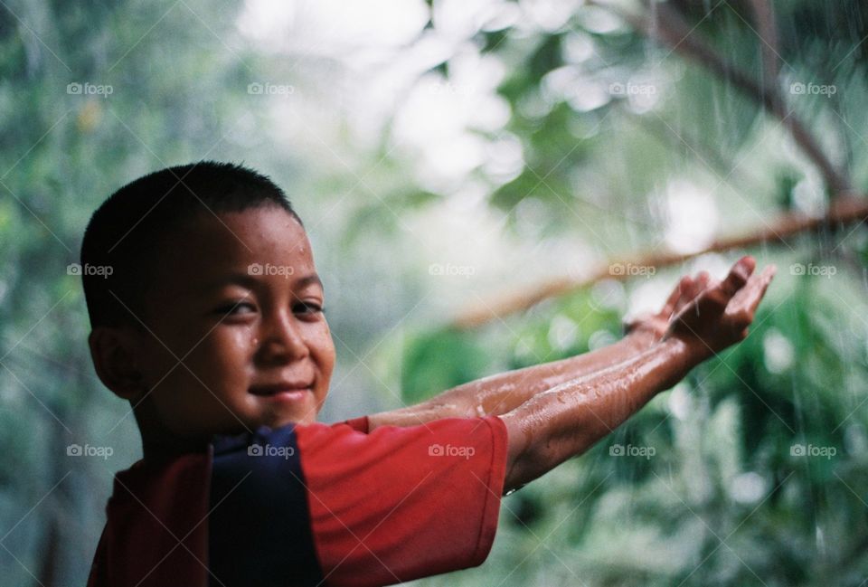 The little boy in the rain, he looks happy.