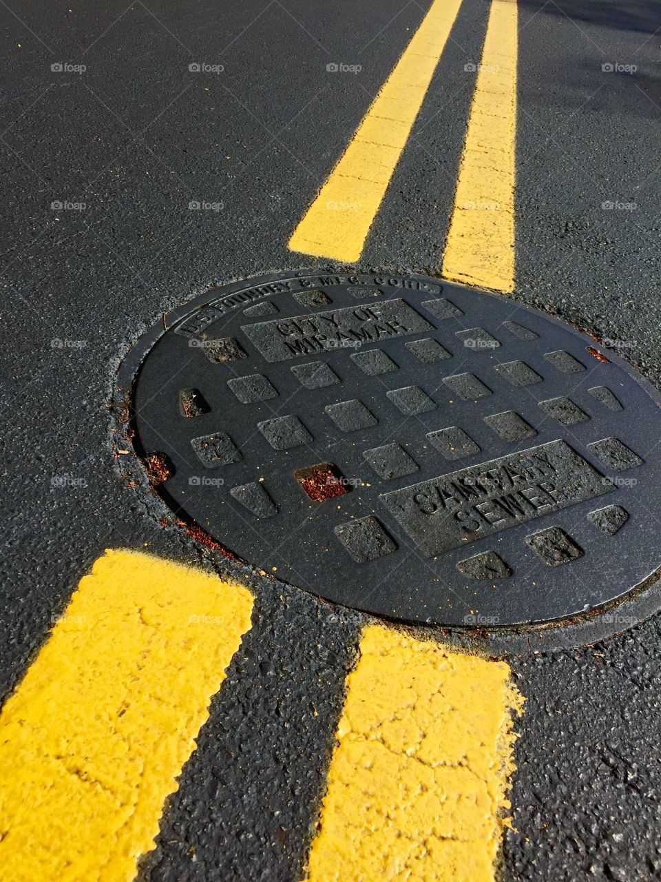 Yellow. Yellow double line on the street with sewer lid.