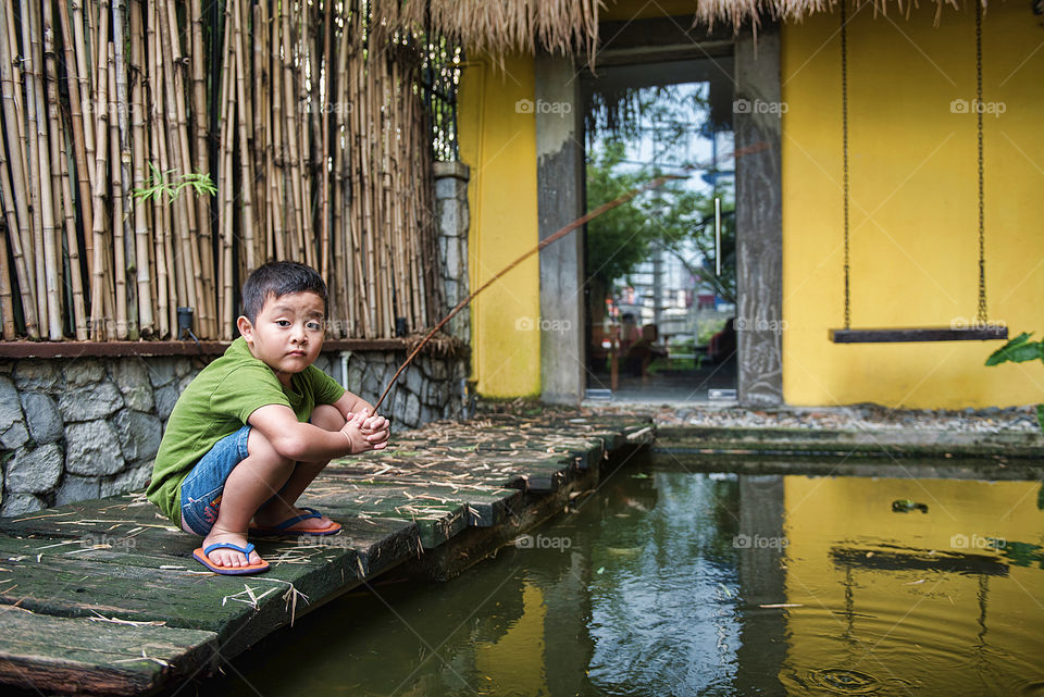 Asian boy fishing in pool