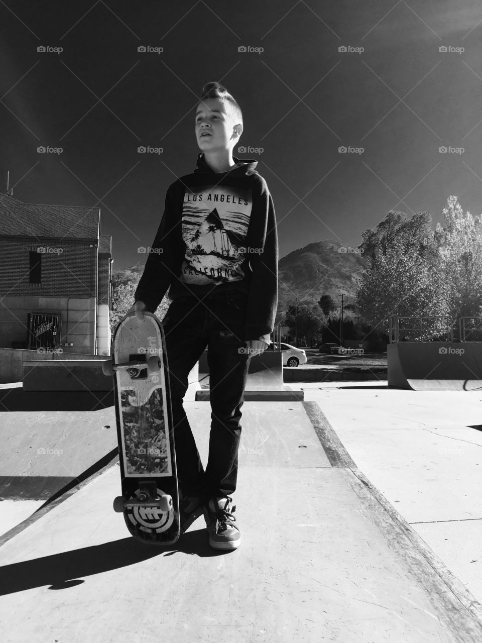 Boy holding skateboard at skateboard park