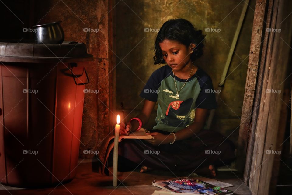 little girl studying in candle light