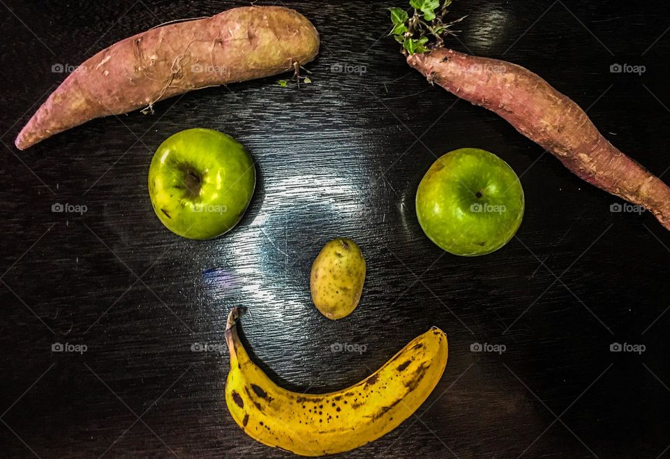 Funny fruity and veggie face made out of sweet potato, apples, banana and a potato for a nose