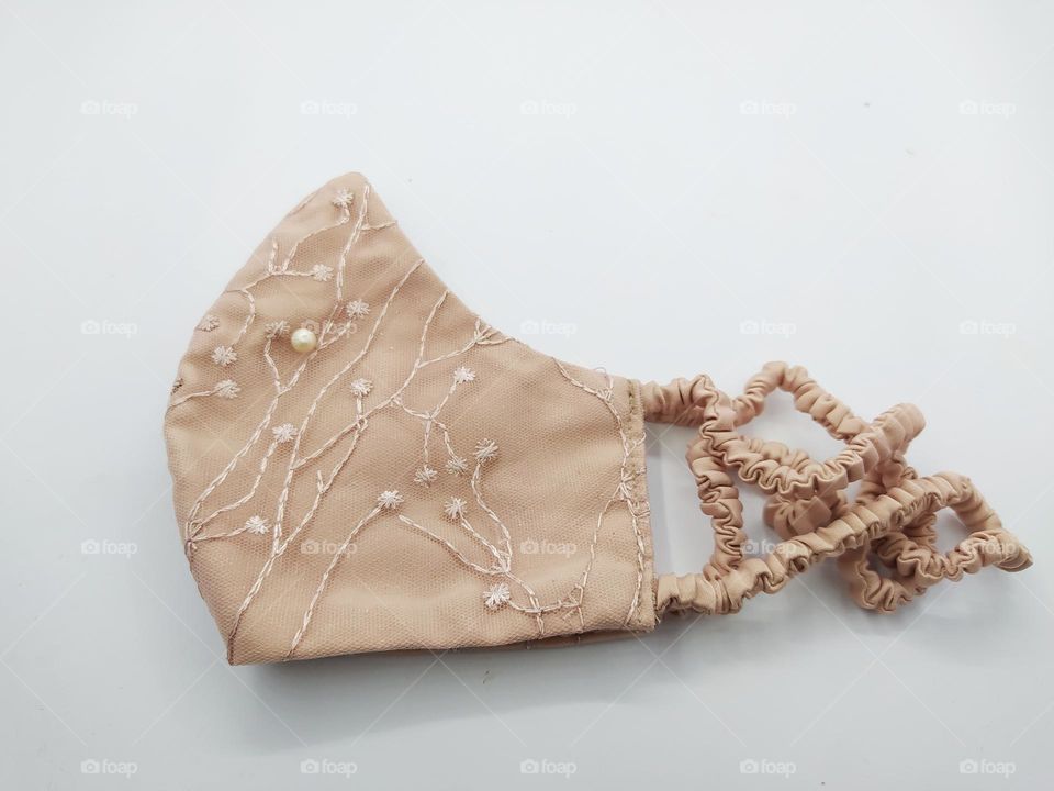 Homemade hijab mask from light brown brocade fabric. Luxury cloth masks. Isolated on a white background.