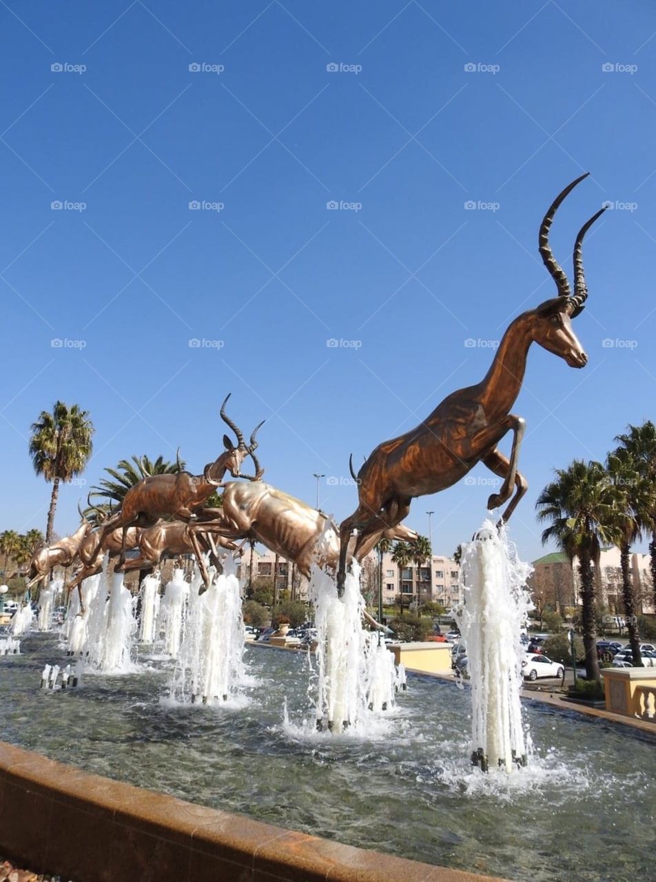 Gold Reef City, Johannesburg, South Africa. This fountain with its leaping golden impala was the first thing I saw during my visit. The impala shone in the winter sunlight as they jumped trough the fountain.m
