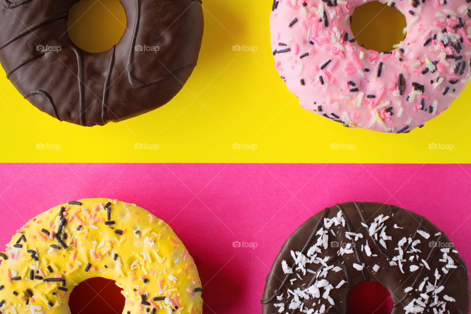 Sweet colourful donuts on pink and yellow background in pop art style.