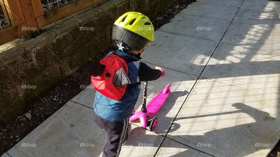 Toddler with scooter wearing helmet