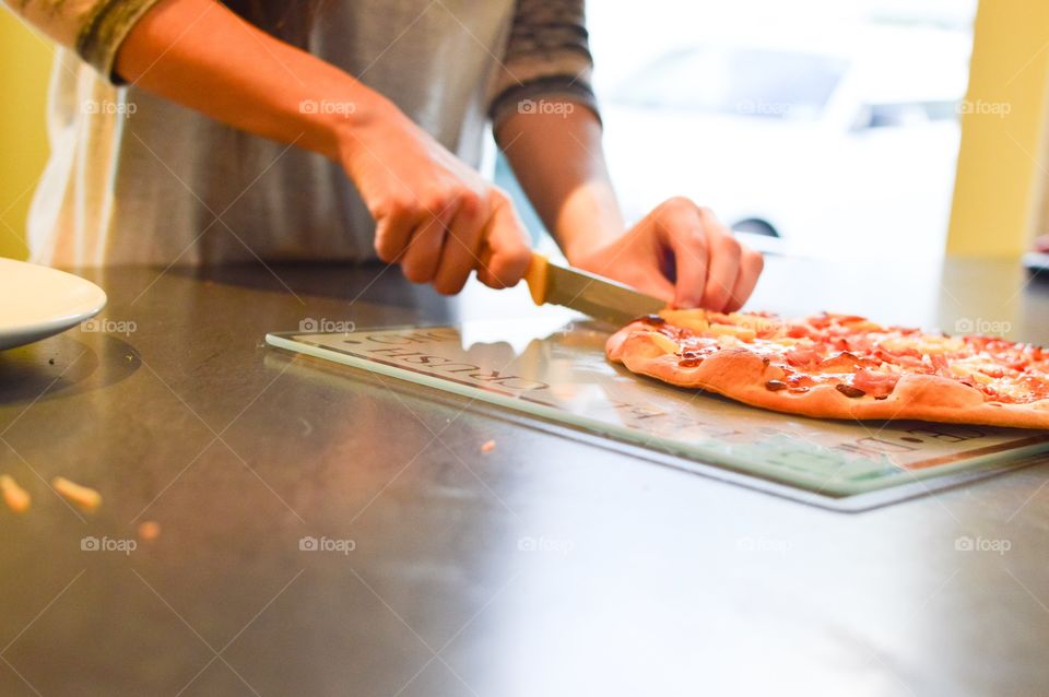 Women slicing pizza with knife